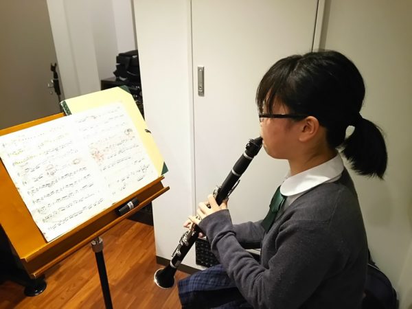 楽譜を見ながらクラリネットを演奏する学生
