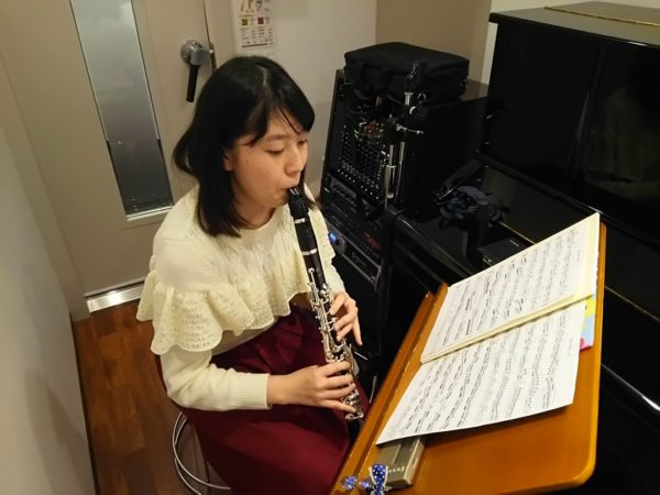 スタジオで楽譜を注意深く見ながらクラリネットを演奏する生徒