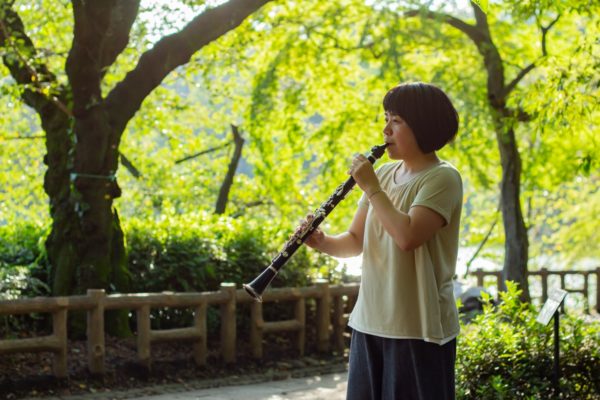 緑がきれいな公園で演奏するクラリネット奏者
